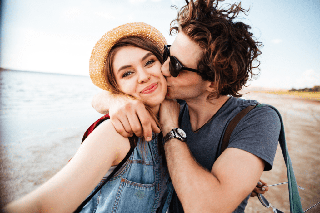 Casal sorrindo em momento de carinho à beira do mar, representando os vínculos emocionais abordados em Os 4 Temperamentos e Como Eles Influenciam o Relacionamento a Dois.